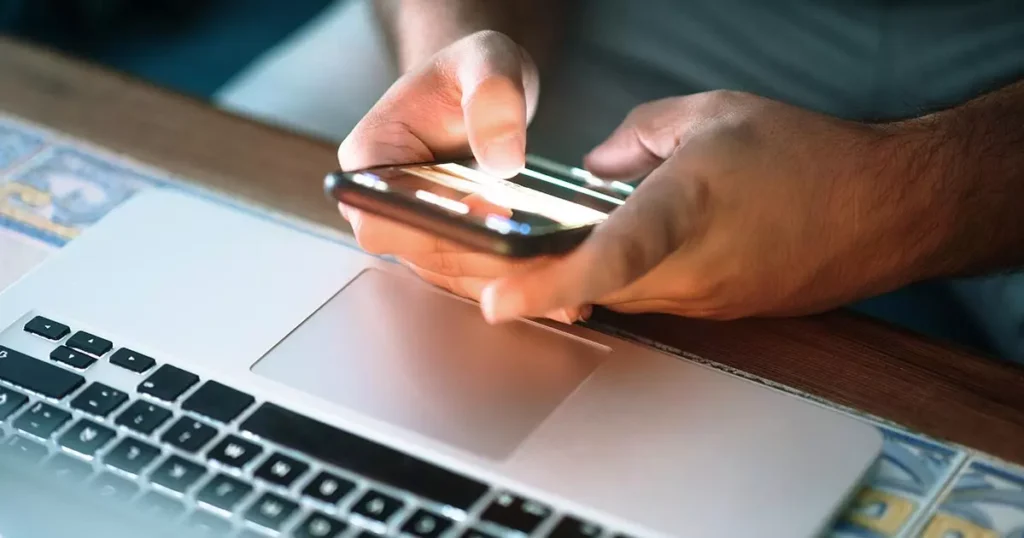 Tillgänglighetsanpassning i fokus - en person använder mobil framför laptop.