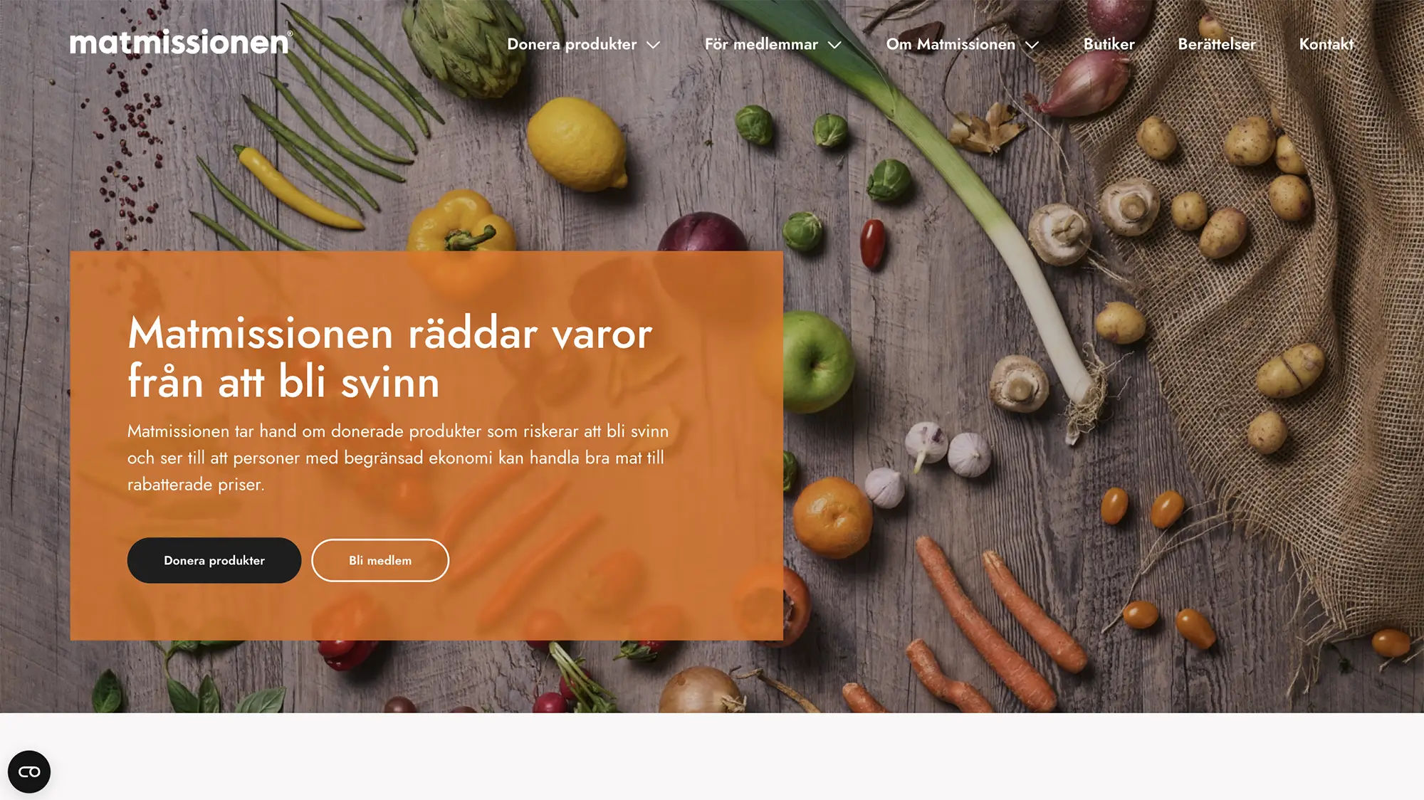 Skärmbild över första sektionen på Matmissionen webbplats. En stor bakgrundsbild med matvaror utspridda på ett träbord och en ruta ovanpå med låg opacitet med info och knapp.