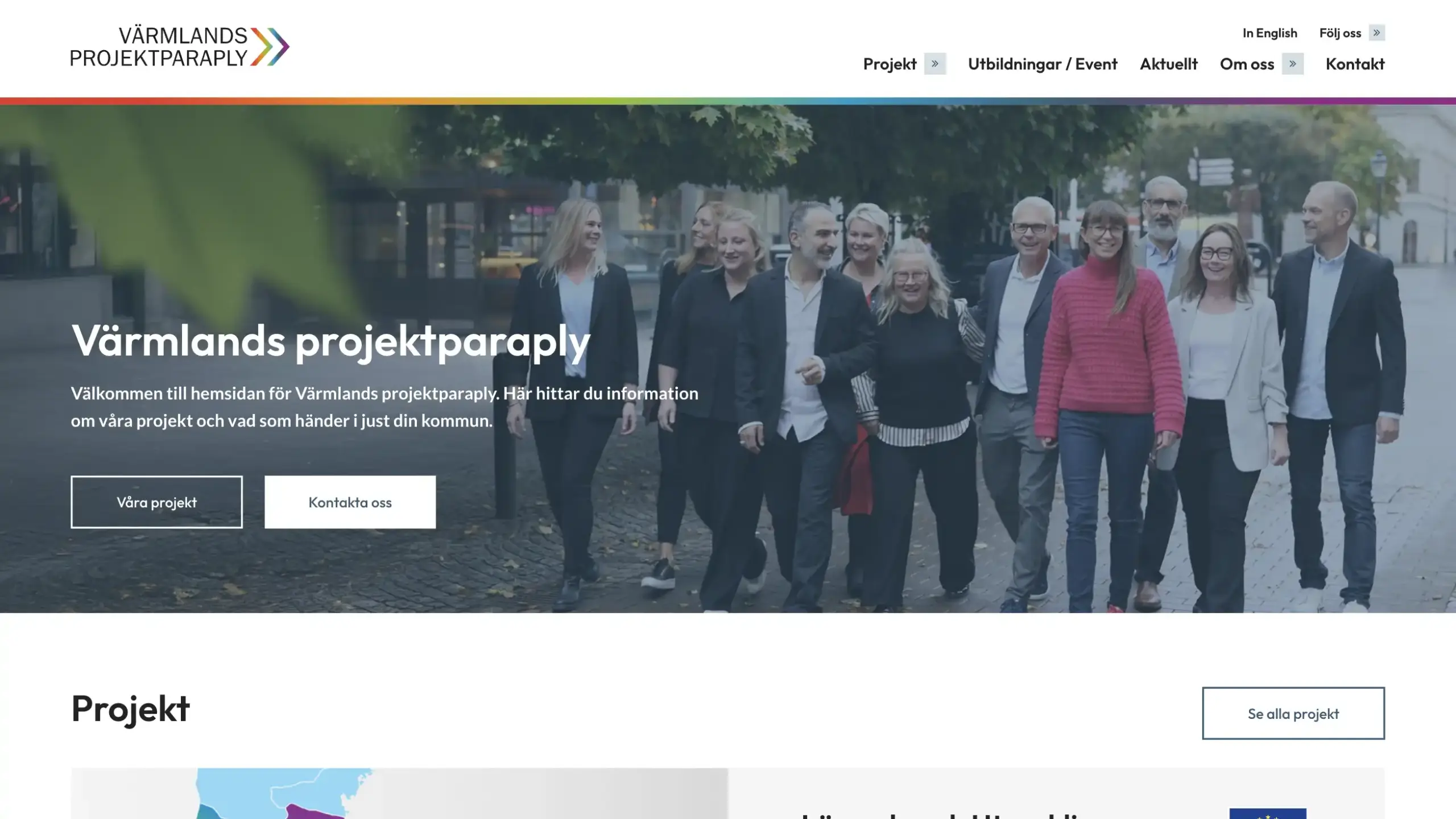 Skärmavbild över startsidan på Värmlands projektparaply. Heron består av en bakgrundsbild med människor och en mörkare overlay med text och knappar.