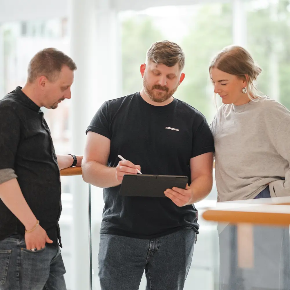 Tre personer som diskuterar design med en surfplatta.